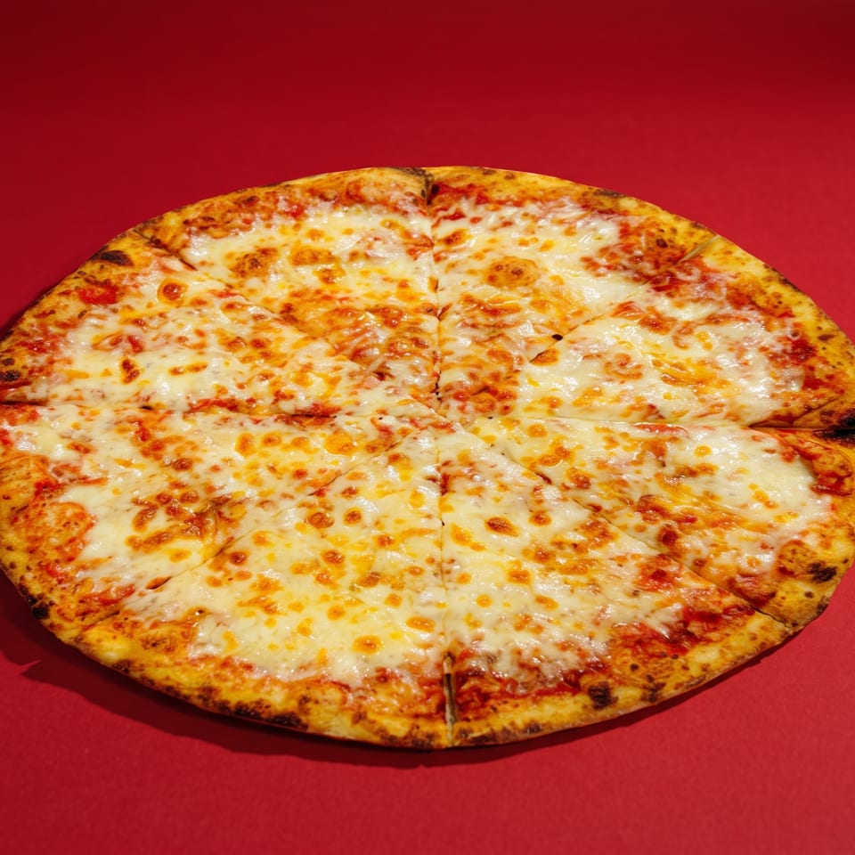 A whole cheese pizza, cut into slices, on a vibrant red background.